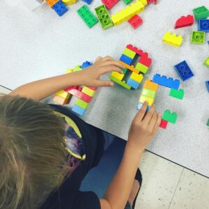 child building letters of the English alphabet out of Legos