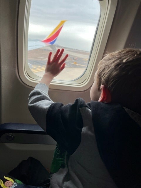 child inside of a flying airplane, looking out the window