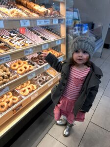child standing and pointing to a display of donuts