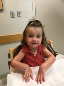 child with feeding tube sitting at a table and smiling
